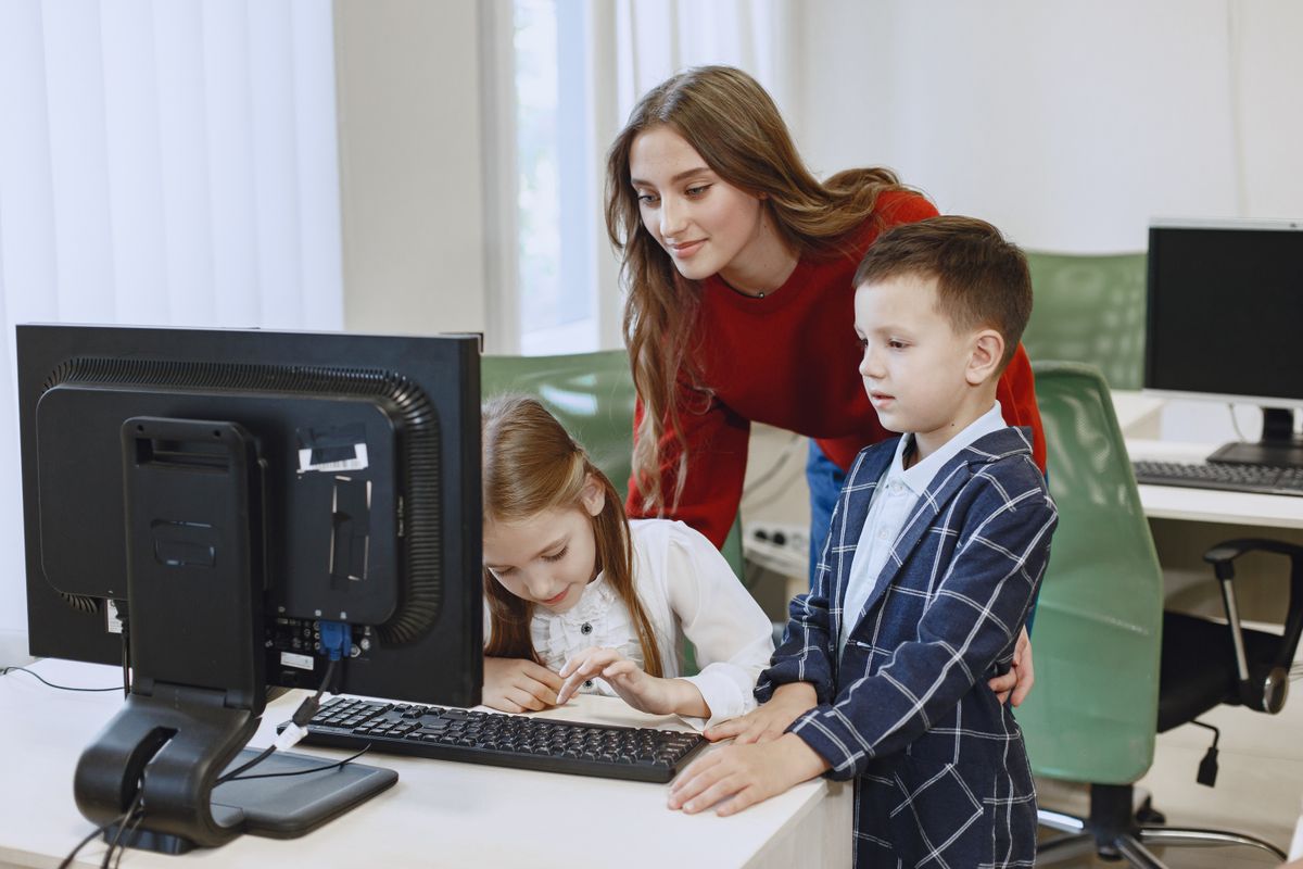 Teacher guiding children during a computer lesson